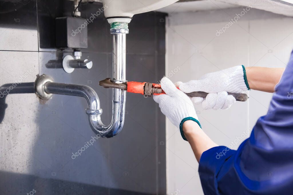 Sanitärinstallateur montiert Leitungen im Bad